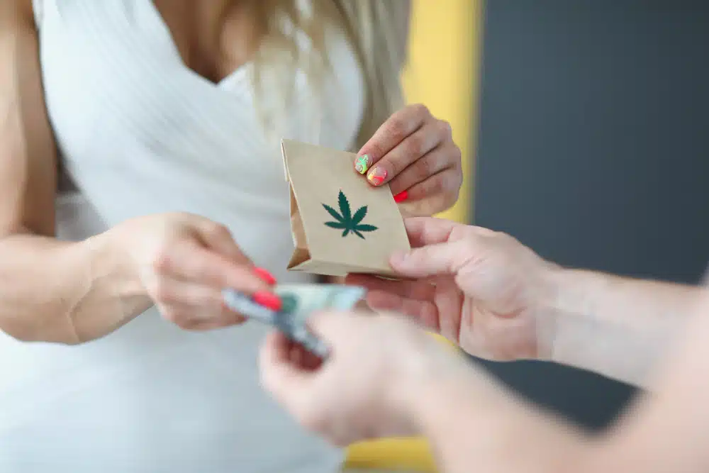 Woman in White Dress receiving bag with cannabis leaf